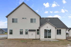 Back of property featuring stucco siding, a patio, and a shingled roof