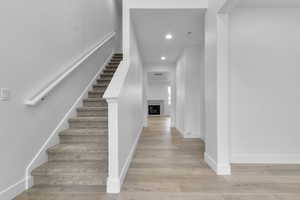 Stairs with recessed lighting, a fireplace, and wood finished floors