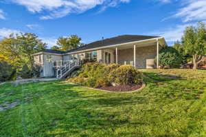 Back of house with a yard, stairway, brick siding, deck and covered patio.