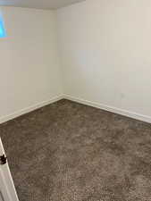 Spare room with baseboards and dark colored carpet