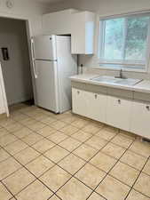 Kitchen with white cabinetry, freestanding refrigerator, light countertops, and light tile patterned floors