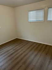Empty room featuring dark wood-style flooring and baseboards