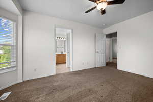 Unfurnished bedroom with light colored carpet, ceiling fan, and ensuite bath