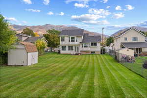 Rear view of house featuring a shed, a fenced backyard, and a mountain view