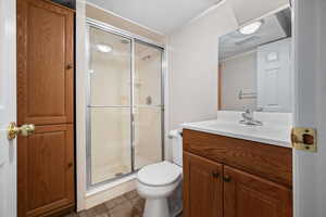 Bathroom with vanity, a textured ceiling, a stall shower, and tile patterned flooring