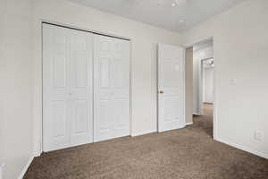 Unfurnished bedroom featuring carpet floors, a closet, and a ceiling fan