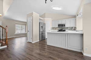 Kitchen with a peninsula, lofted ceiling, stainless steel appliances, tasteful backsplash, and light countertops