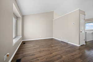Empty room with dark wood-type flooring and vaulted ceiling