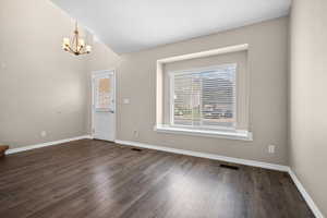 Foyer entrance featuring dark wood-style floors, a chandelier, and vaulted ceiling