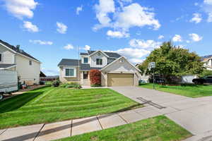 Traditional-style home featuring a front yard, driveway, brick siding, and a garage