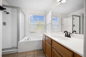 Bathroom featuring vanity, light tile patterned floors, a stall shower, and a bath