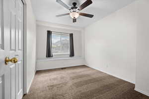 Unfurnished bedroom featuring carpet flooring, a closet, and ceiling fan