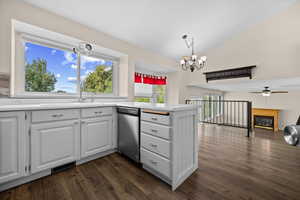 Kitchen featuring white cabinetry, a peninsula, light countertops, dark wood finished floors, and a glass covered fireplace