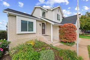 View of front of home featuring brick siding and roof with shingles