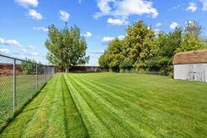 Fenced backyard featuring a storage shed
