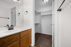 Bathroom featuring vanity, dark carpet, and a walk in closet