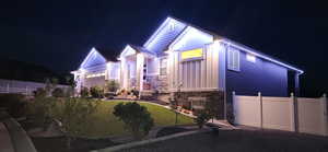 Property exterior at night featuring stone siding, board and batten siding, and a garage
