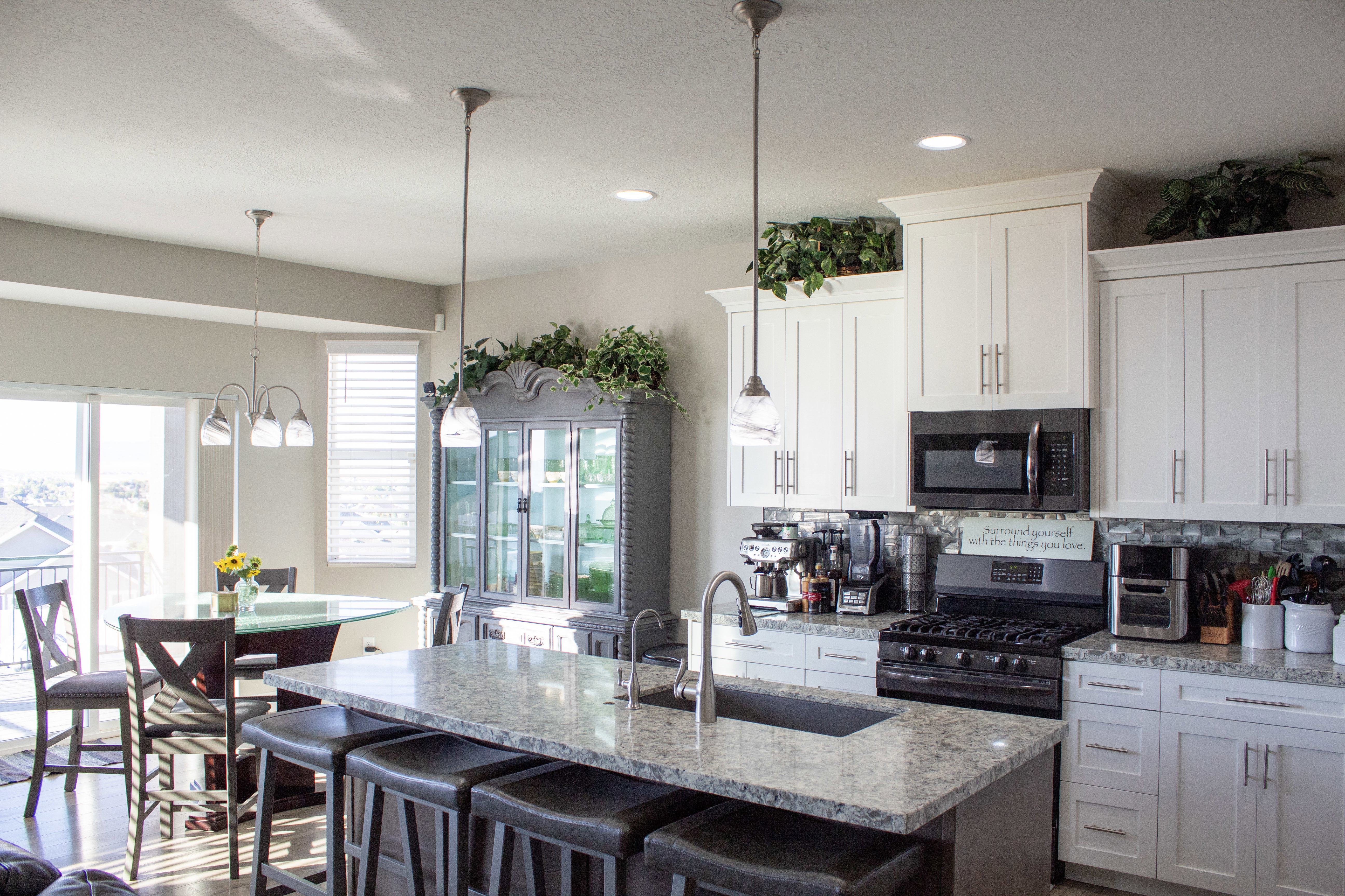 Kitchen with stainless steel appliances, white cabinets, light stone countertops, a kitchen breakfast bar, and recessed lighting