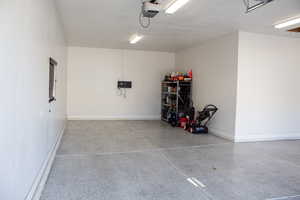 Garage featuring baseboards and a garage door opener
