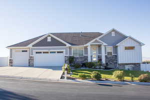 Craftsman-style house featuring board and batten siding, driveway, an attached garage, and stone siding