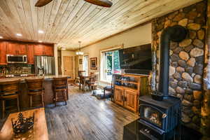 Living area featuring a wood stove, wooden ceiling, dark wood-type flooring, recessed lighting, and a chandelier