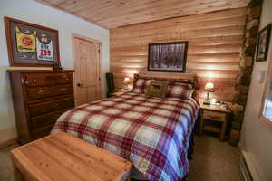 Bedroom featuring a closet, light carpet, log walls, wood ceiling, and a baseboard radiator