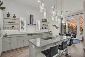 Kitchen featuring open shelves, light stone countertops, light wood-style flooring, a breakfast bar, and recessed lighting