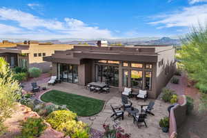 Rear view of house with stucco siding, a mountain view, an outdoor fire pit, and a patio area