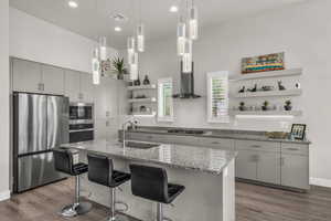 Kitchen featuring open shelves, appliances with stainless steel finishes, light stone countertops, pendant lighting, and recessed lighting