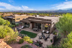 Rear view of property with stucco siding, a mountain view, a fire pit, and a patio