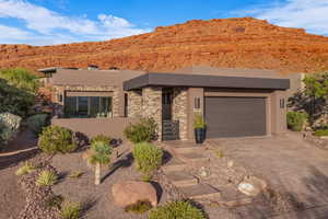 View of front of house with stucco siding, driveway, a mountain view, and stone siding