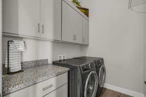 Laundry area with washing machine and clothes dryer, dark wood-style flooring, and cabinet space