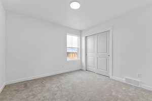 Unfurnished bedroom with light colored carpet and a closet