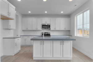 Kitchen featuring white cabinets, recessed lighting, appliances with stainless steel finishes, a kitchen island with sink, and backsplash