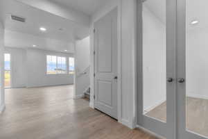 Corridor featuring recessed lighting, light wood-style floors, and stairway