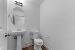 Half bath with baseboards and wood finished floors