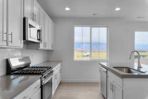 Kitchen with appliances with stainless steel finishes, white cabinets, recessed lighting, and backsplash