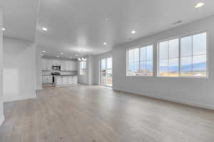 Unfurnished living room featuring recessed lighting, a chandelier, a mountain view, and light wood finished floors