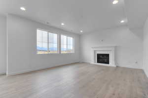 Unfurnished living room featuring a mountain view, recessed lighting, light wood-type flooring, and a glass covered fireplace