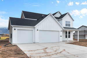 Modern farmhouse with a shingled roof, driveway, board and batten siding, a porch, and an attached garage