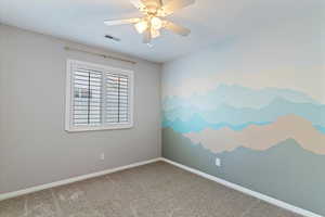 Carpeted empty room with baseboards and a ceiling fan