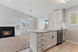 Kitchen with light countertops, white cabinets, light carpet, a peninsula, and lofted ceiling