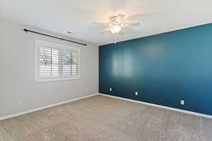 Empty room featuring carpet floors and a ceiling fan