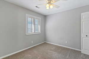 Carpeted empty room featuring baseboards and ceiling fan