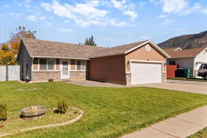 Ranch-style home featuring driveway, a shingled roof, an attached garage, brick siding, and a mountain view