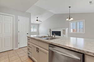 Kitchen featuring dishwasher, light countertops, open floor plan, lofted ceiling, and light tile patterned floors