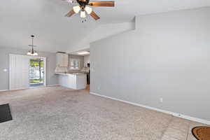 Unfurnished living room featuring lofted ceiling, a chandelier, light carpet, a ceiling fan, and light tile patterned floors