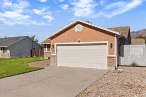 Single story home featuring brick siding, driveway, stucco siding, and a garage