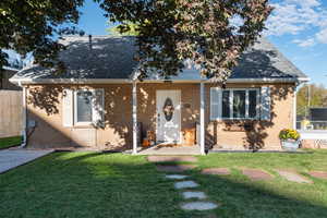 View of front of property with a shingled roof and brick siding