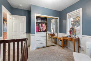Bedroom featuring a closet, light colored carpet, and a textured ceiling